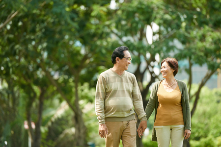 mature couple walking outdoors holding hands and smiling