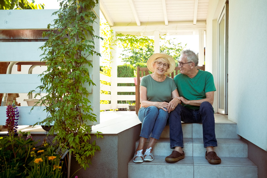Happy older couple sitting together on their porch steps.