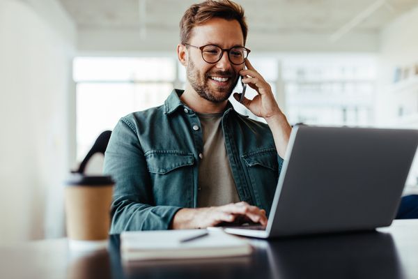 Woman working on laptop with earbuds looking out window