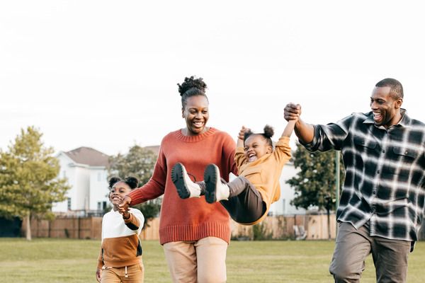 mom and dad with two young children having fun in park