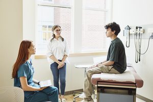 nurse consulting with teen boy and mother in clinic
