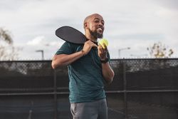 Young man smiling pickleball court jpg