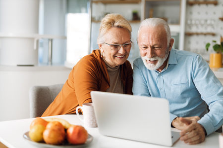smiling senior couple reading on computer in ktichen