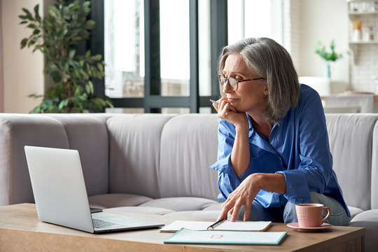 senior woman working on computer on couch in living room