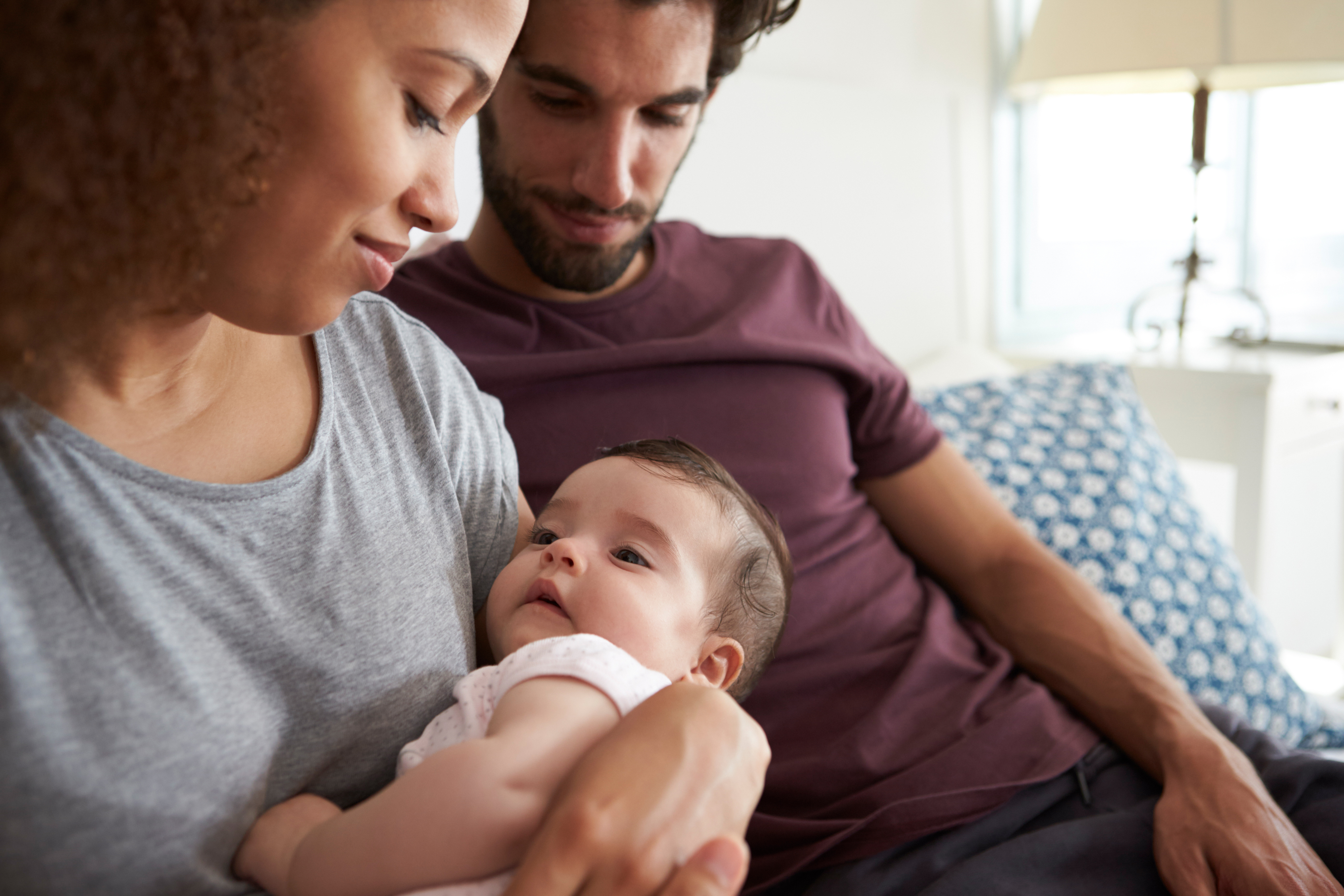 mother cradling infant as dad looks on