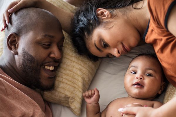 Parents laying on bed with baby between them
