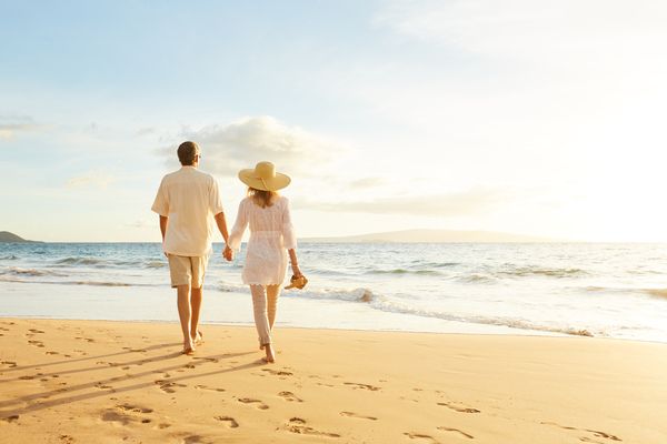 couple holding hands walking on beach